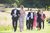 A group of people walking in evening wear down a mown grass path