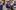 4-OperaFirst-©-Julian-Guidera A group of children in purple school uniform stand singing around a piano.