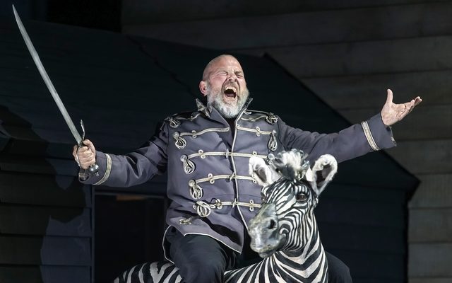 A man in military dress sits on top of a zebra holding a sword. An image from Garsington Opera's 2023 performance of 'Mitridate, re di Ponto' by Mozart..